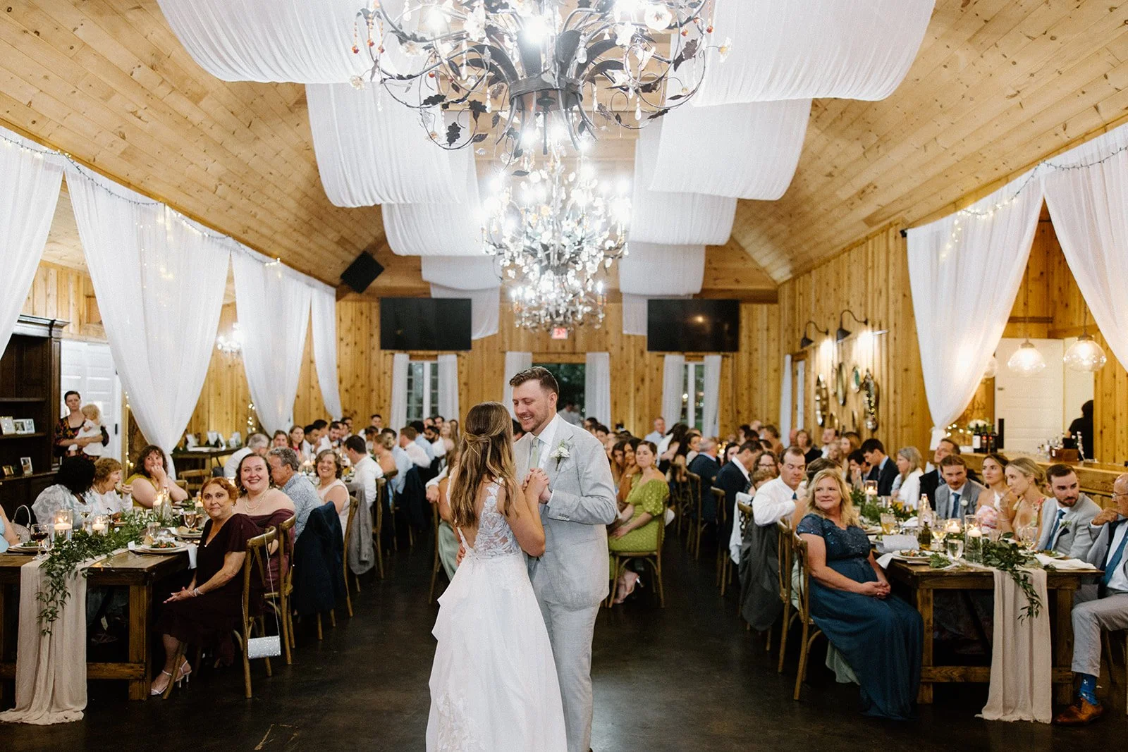 bride-and-groom-first-dance-chandelier-rustic-reception.jpg