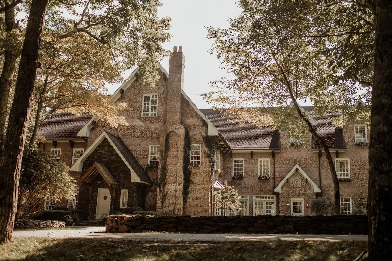Brick estate wedding venue exterior with ivy-covered walls, tall chimneys, and trees