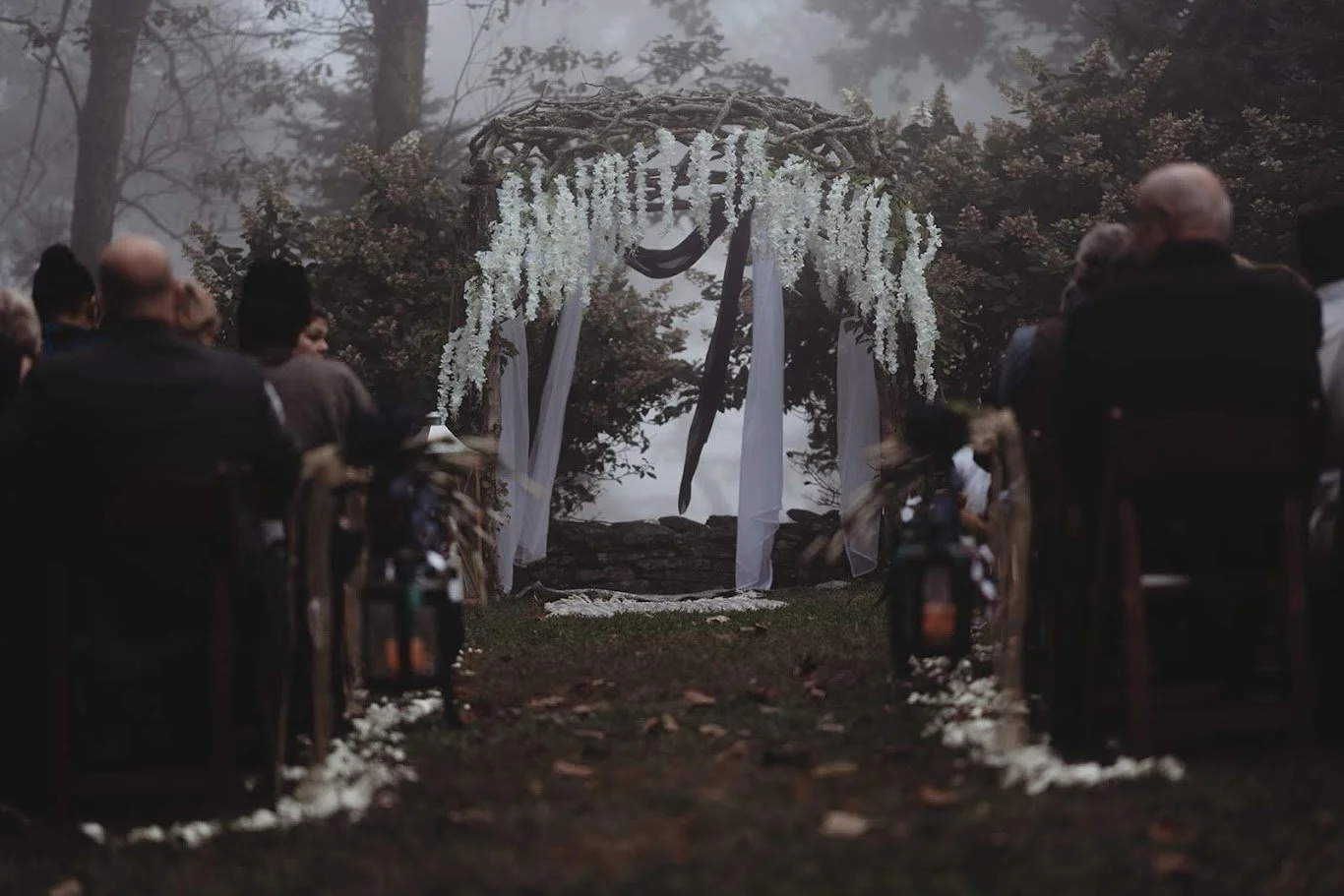 Groomsmen standing together outdoors in a foggy forest setting.