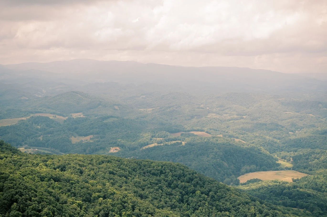 A scenic overlook featuring vast green mountains and a cloudy sky.