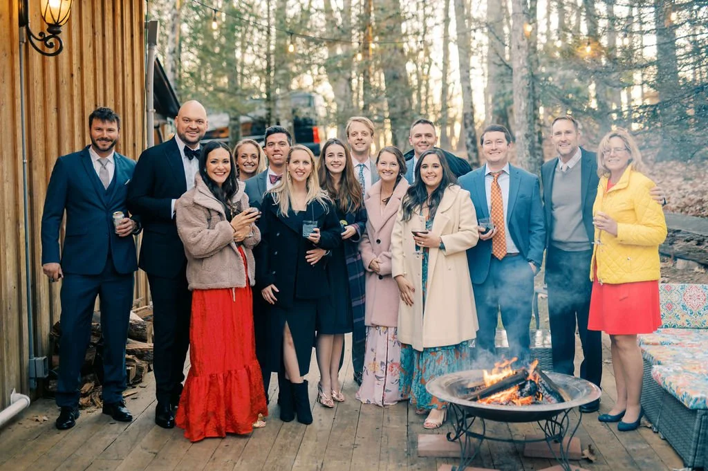 Group gathered around an outdoor fire pit for a photo during an evening celebration