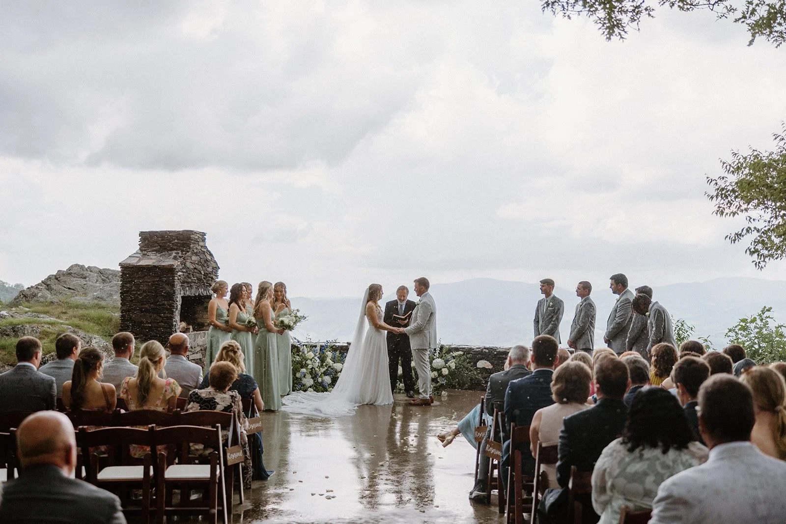Bride and groom exchanging vows during an outdoor mountain overlook wedding ceremony with their wedding party.