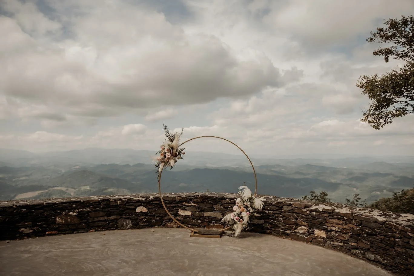 Circular wedding arch with florals on a mountaintop stone terrace with mountain views