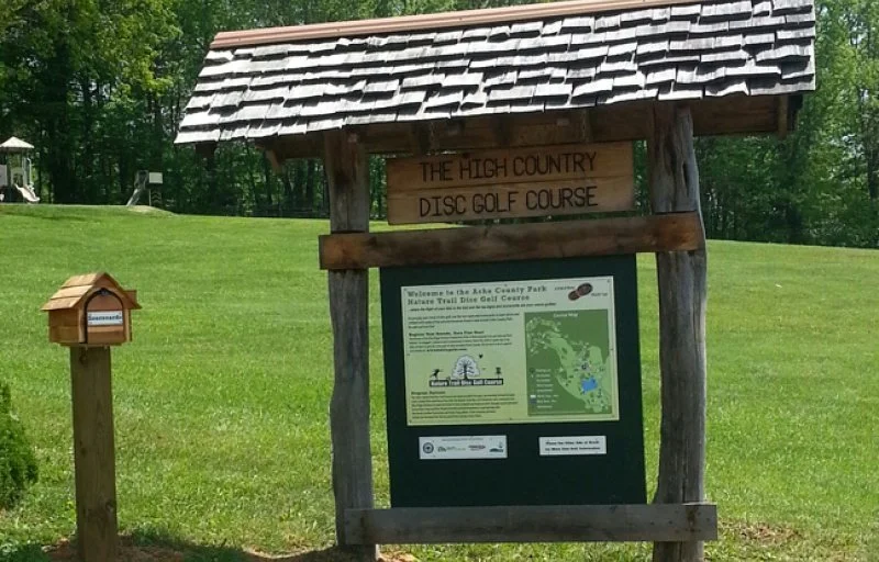 High Country Disc Golf Course sign on a grassy field with trees in the background
