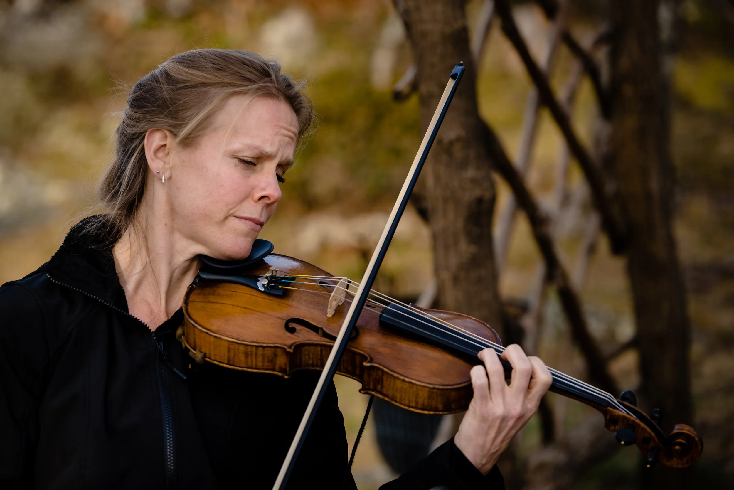 Violinist playing during an outdoor wedding ceremony in a wooded setting