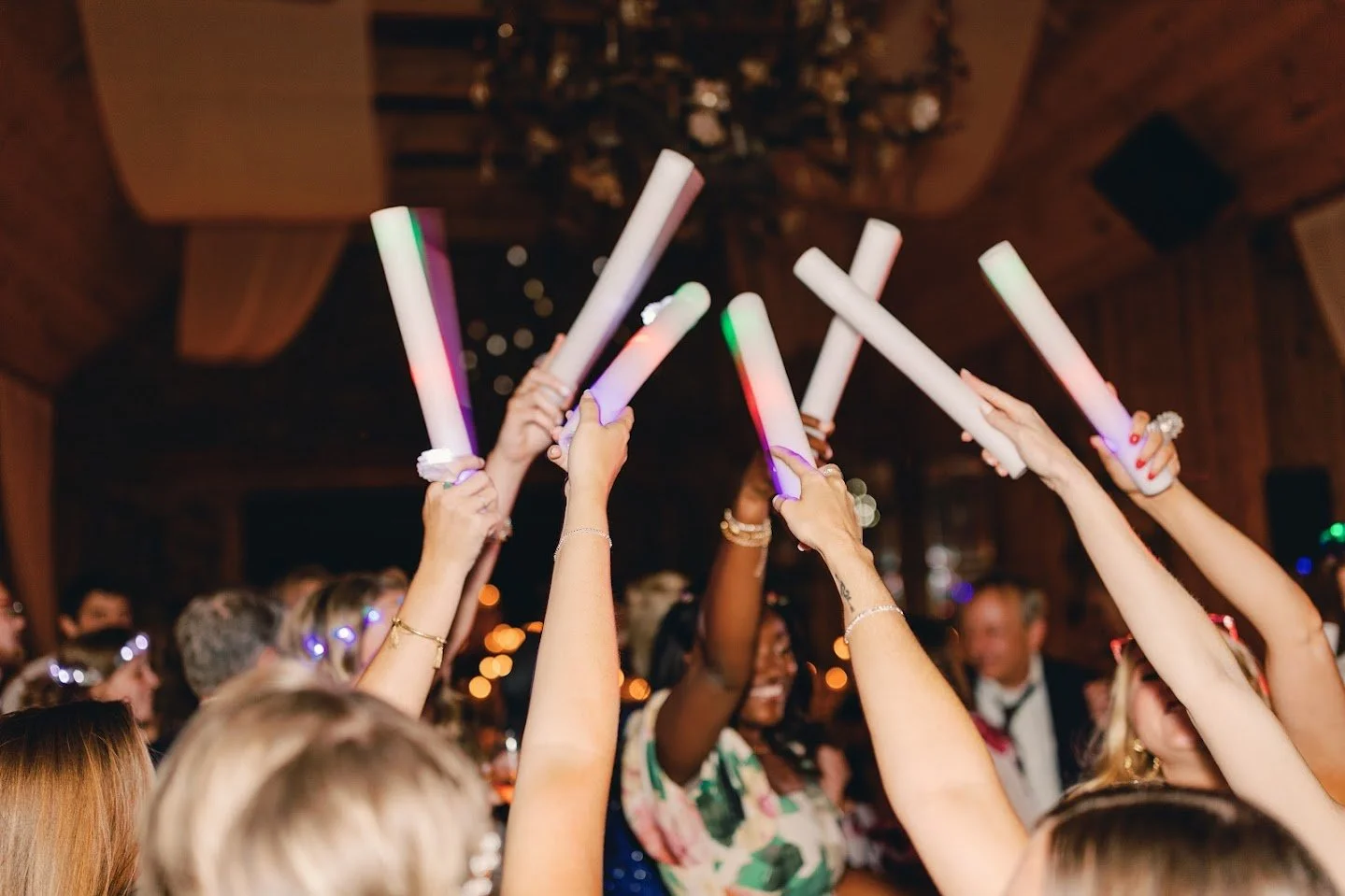 Wedding guests raising glow sticks together on the dance floor.