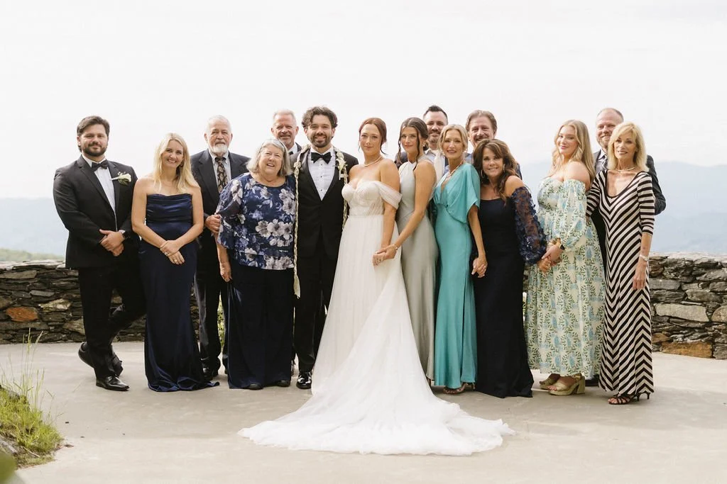 Bride and groom posing with family members in formal attire at a mountain overlook ceremony location.