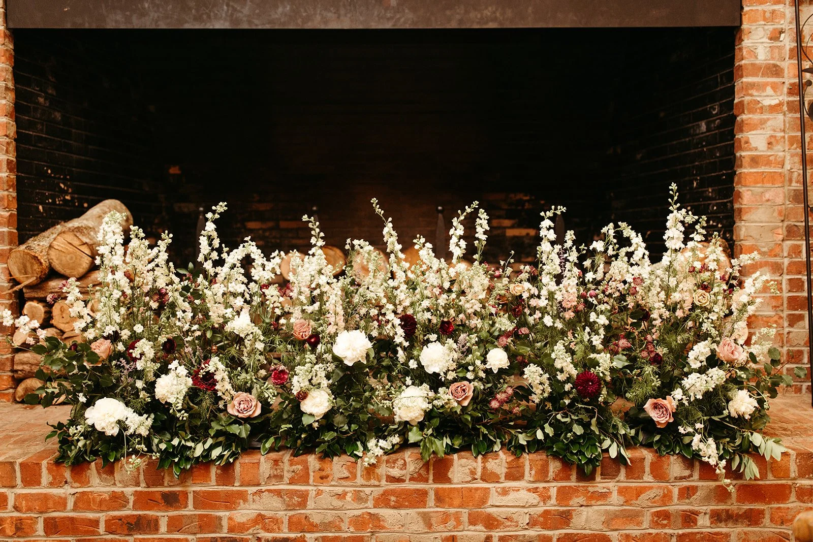 Wedding memory table with framed family photos and candles on a round table against a wooden wall.