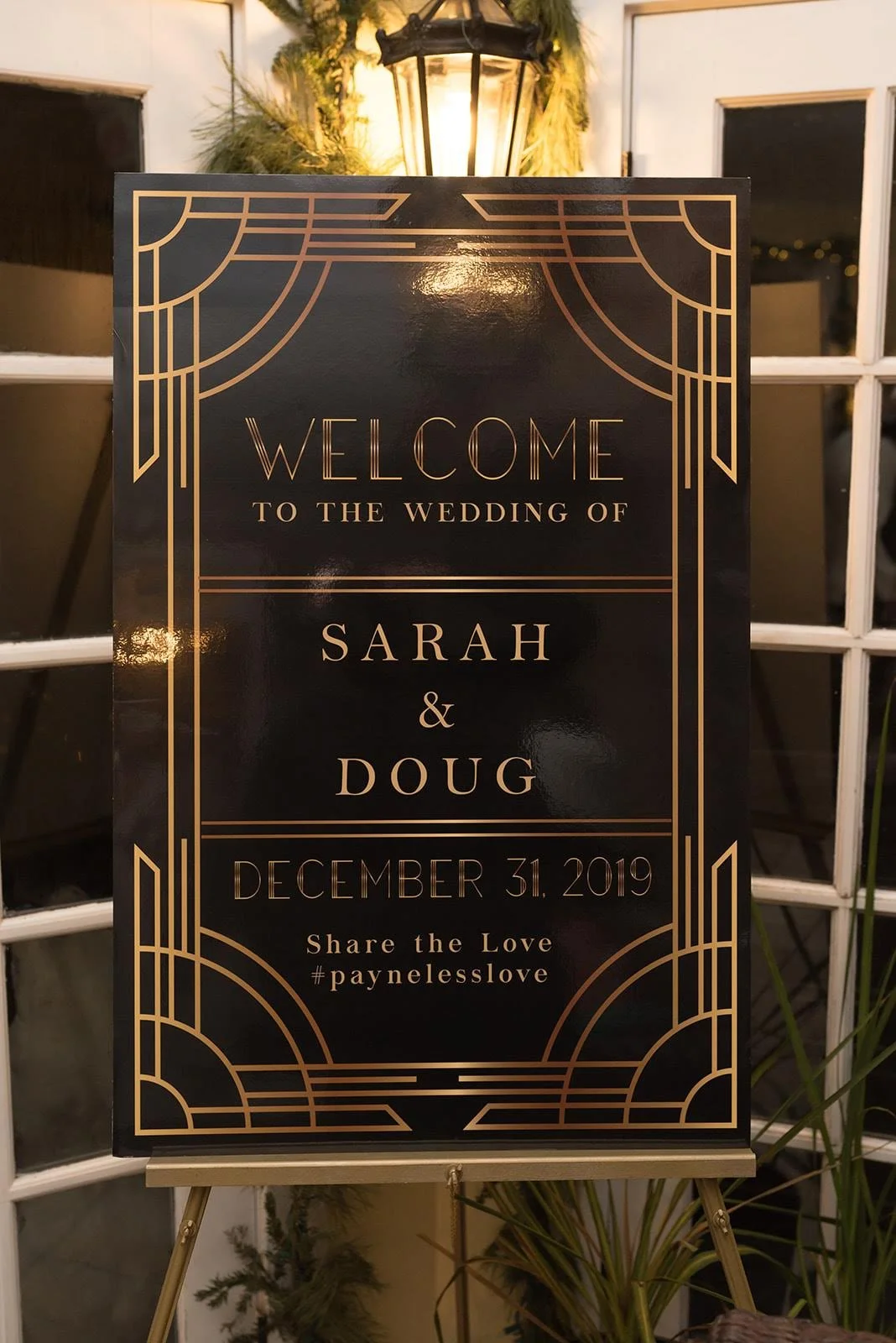 Art deco style welcome sign reading “Welcome to the wedding of Sarah and Doug, December 31, 2019.”