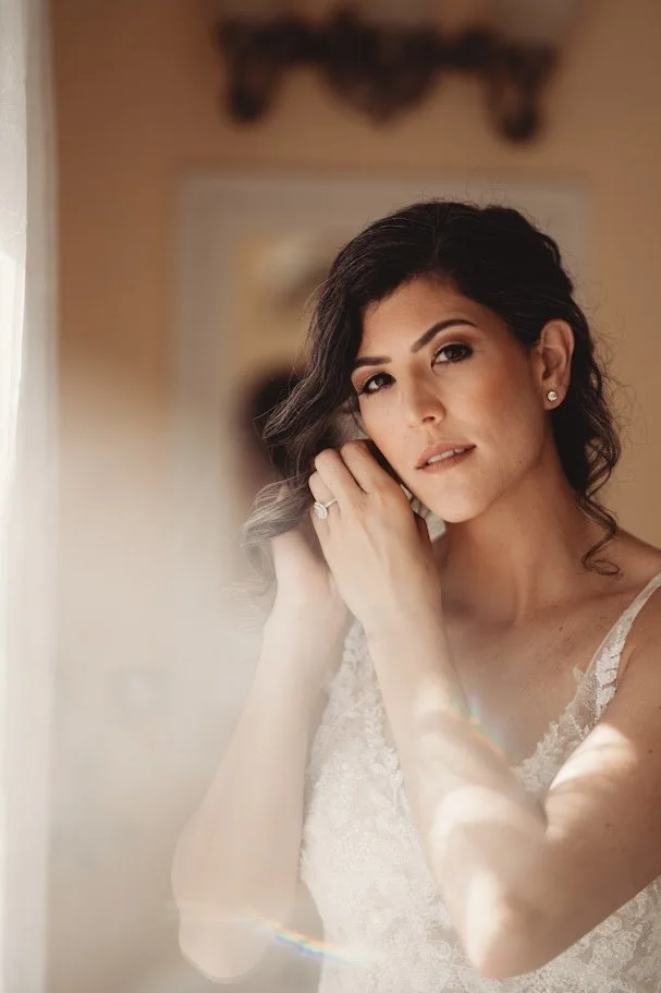 Bride putting on earrings in soft window light during getting-ready portraits