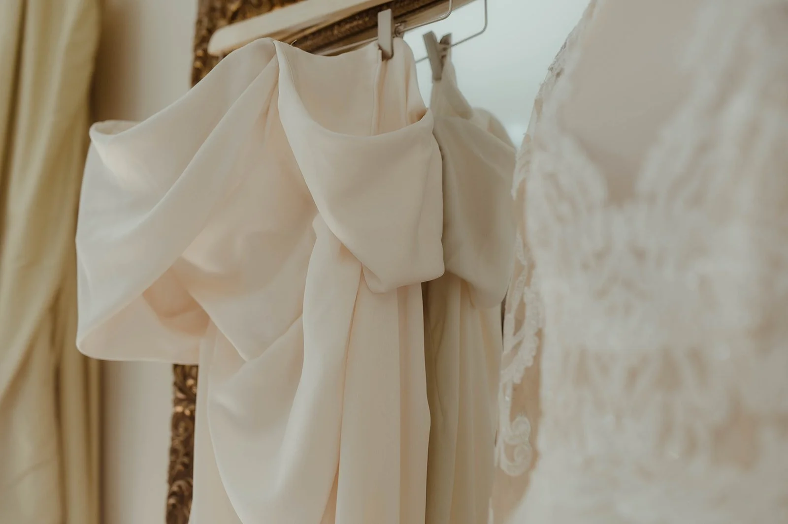 Close-up of a white wedding dress with soft bow fabric and lace details hanging before the ceremony.
