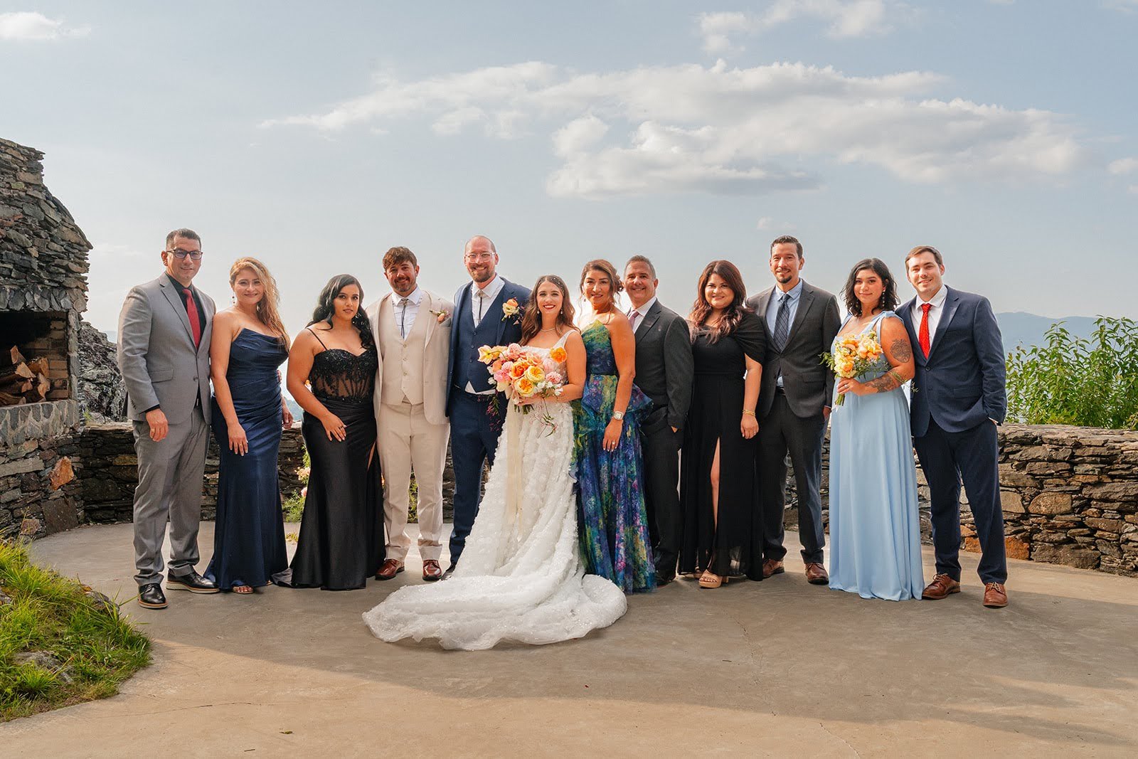 Bride and groom posing with family members at a mountain overlook ceremony site with scenic views behind them.
