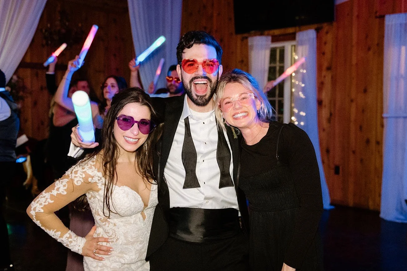 Wedding after-party group photo with glow sticks and colorful party glasses.