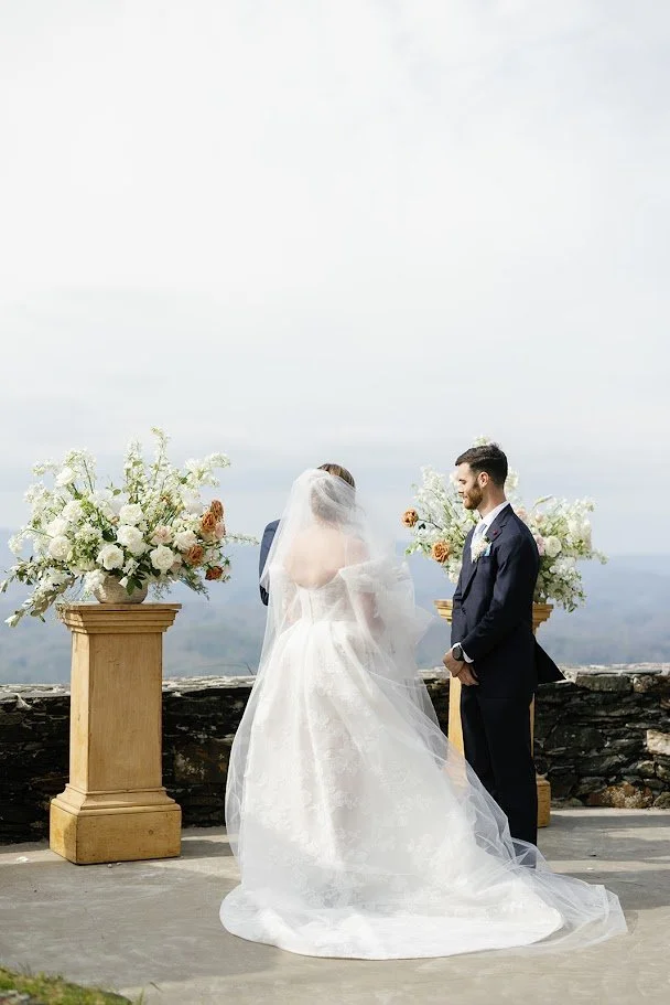 Bride and groom during mountain wedding vows with the bride’s long veil seen from behind