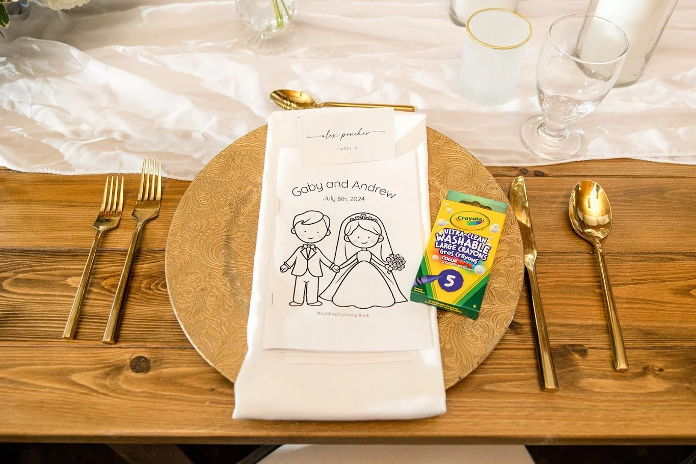 Wedding place setting with a napkin-wrapped kids coloring page and a small box of crayons