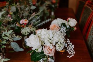 Wedding aisle floral arrangement with white roses, blush roses, hydrangea, and greenery