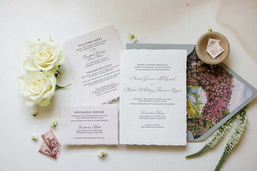Wedding invitation suite on handmade paper with vow book and styling details in a flat lay
