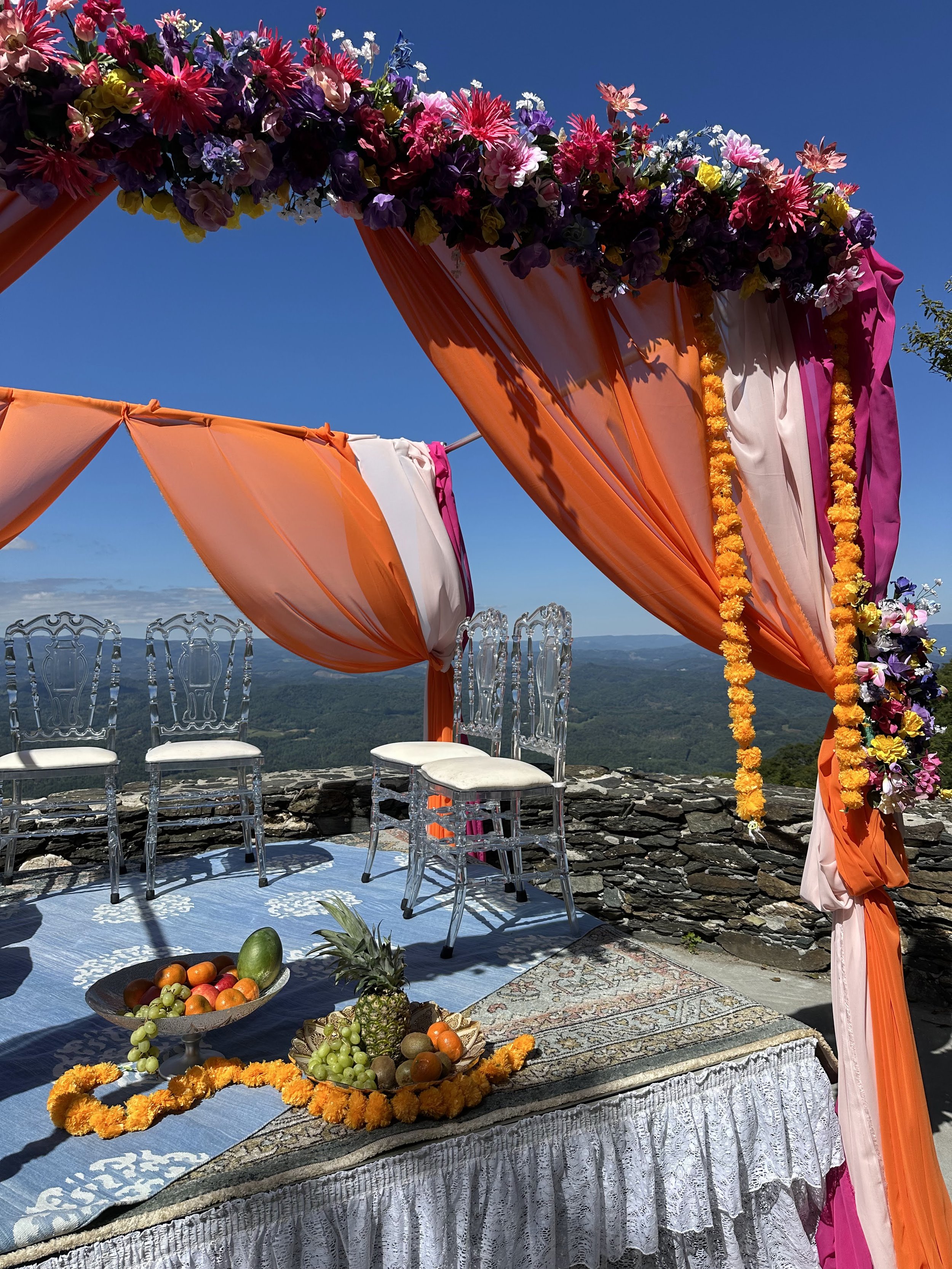 Close-up of a colorful mandap with flowers and marigold garlands set against a mountain view