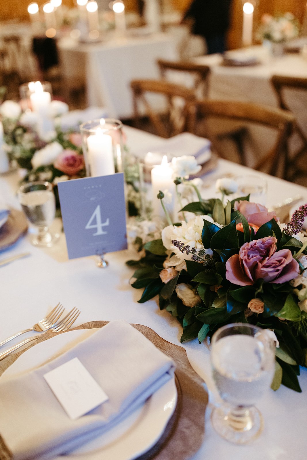 Reception place setting with floral centerpiece, candles, and a table number four card.