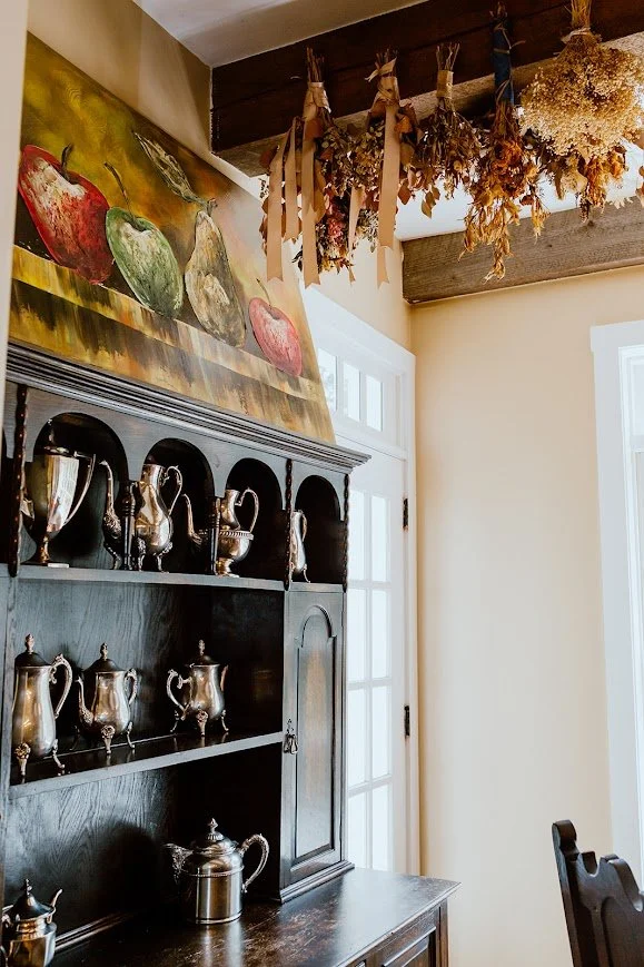 Interior detail of shelves with teapots and hanging dried herbs in a rustic kitchen