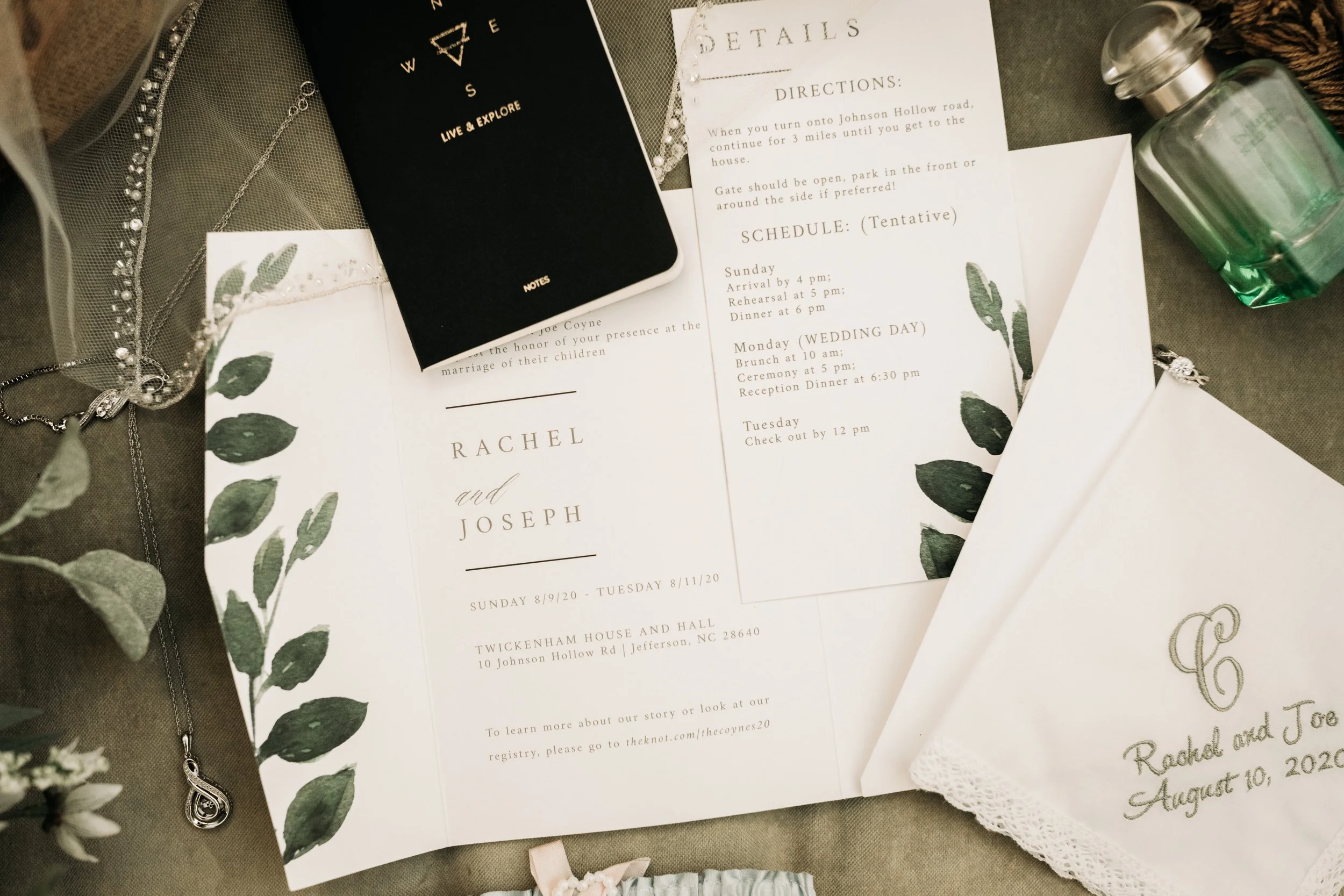 Rachel and Joseph wedding invitation suite with greenery details, jewelry, vow book, and embroidered handkerchief.