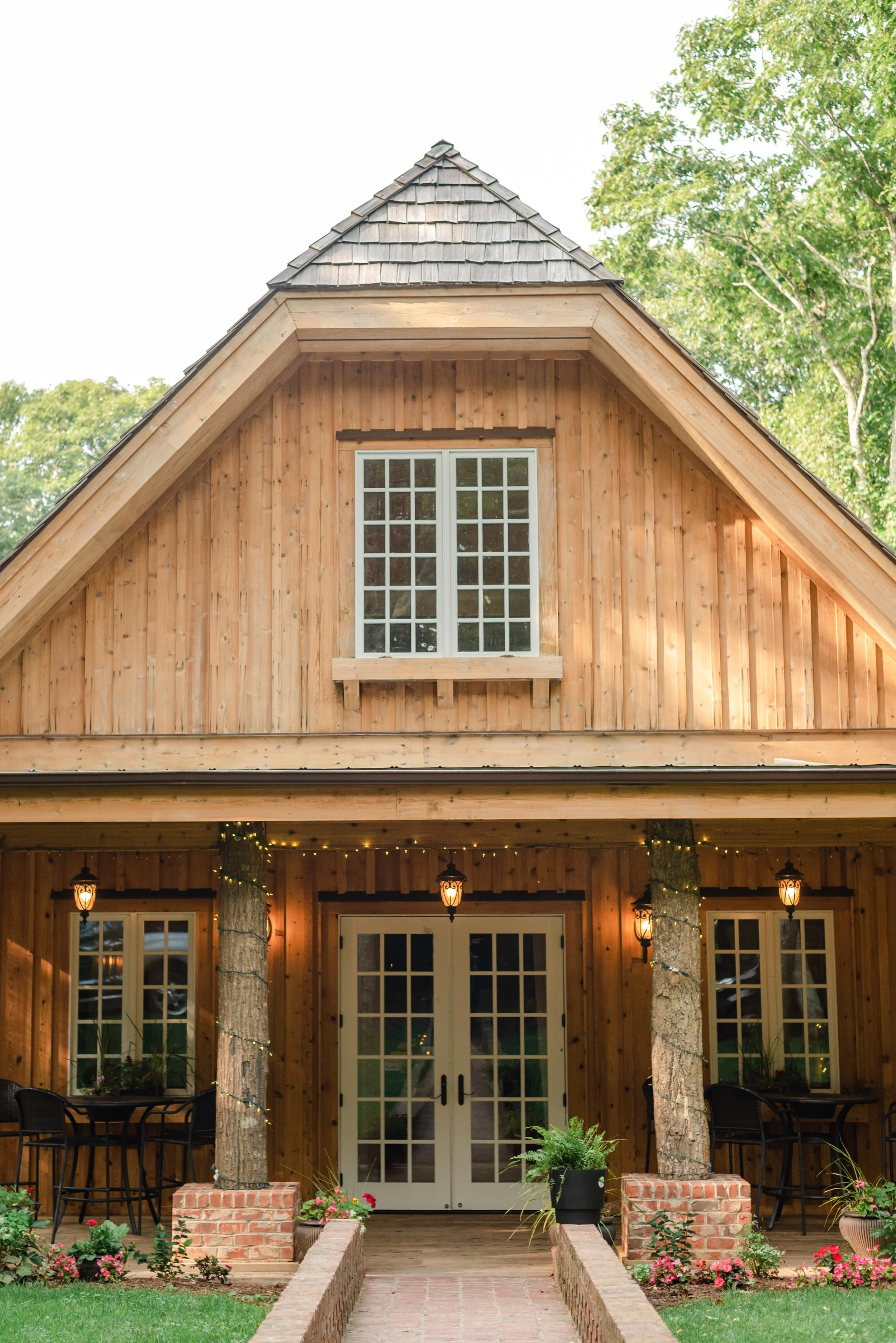 Rustic wooden venue entrance with double doors, string lights, and a gabled roof.