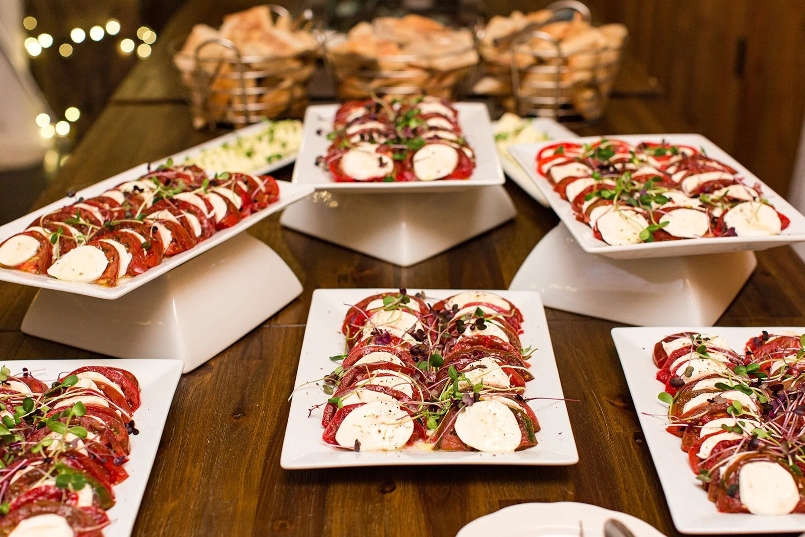 Caprese salad platters with tomato, mozzarella, basil, and balsamic displayed for wedding reception catering.