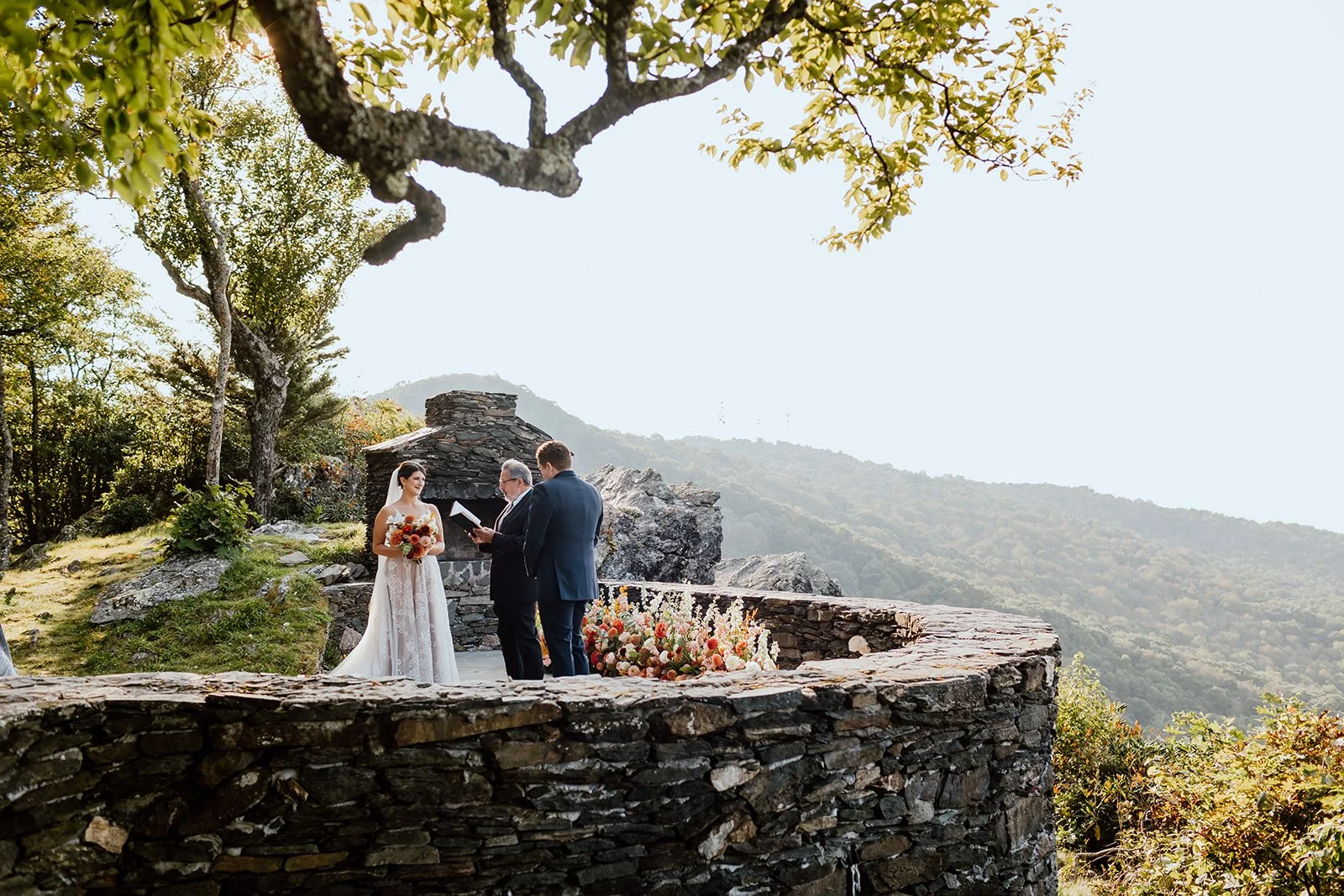 Intimate mountain overlook wedding ceremony on a stone terrace with autumn flowers and scenic valley views.