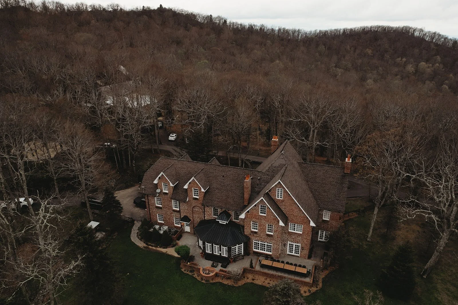 Drone photo of a brick estate in winter with bare trees and mountains beyond