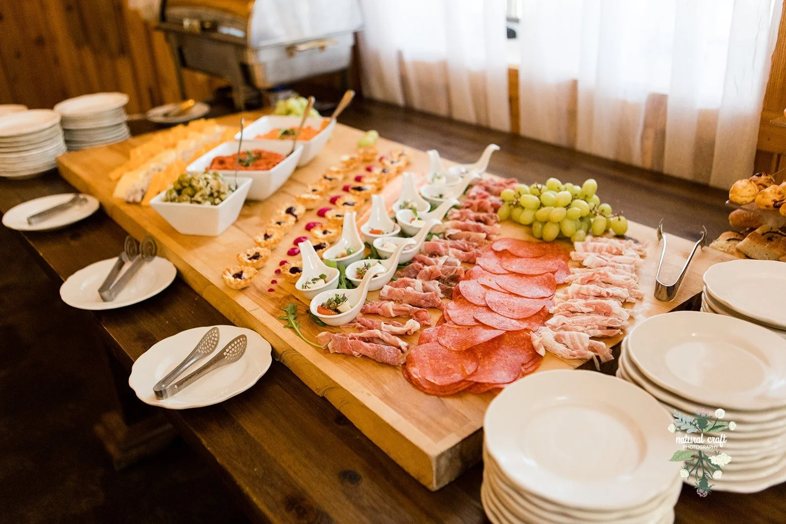 Wedding charcuterie board with sliced meats, cheese, grapes, and small bites for cocktail hour.