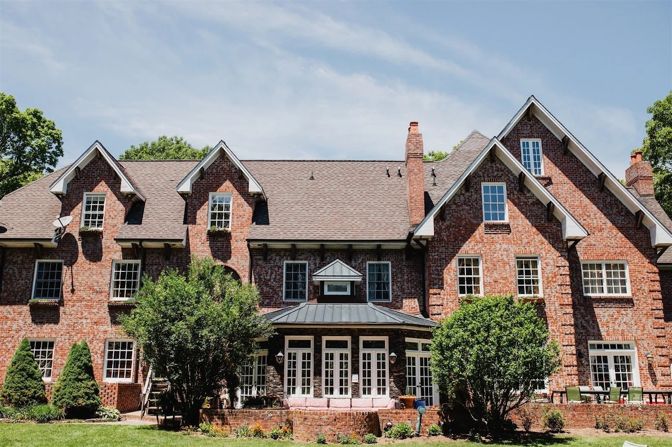 Exterior view of Twickenham House, a large brick building with multiple gables, windows, and a central gazebo-like structure with French doors leading to the backyard and lawn.