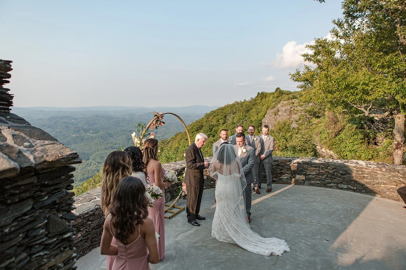 Wide view of an outdoor mountain wedding ceremony with guests and wedding party on a scenic overlook