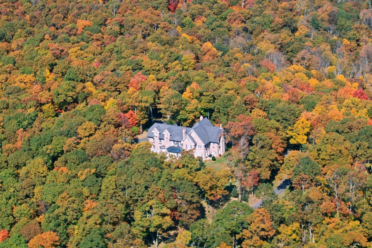Aerial view of Twickenham House & Hall surrounded by colorful fall forest