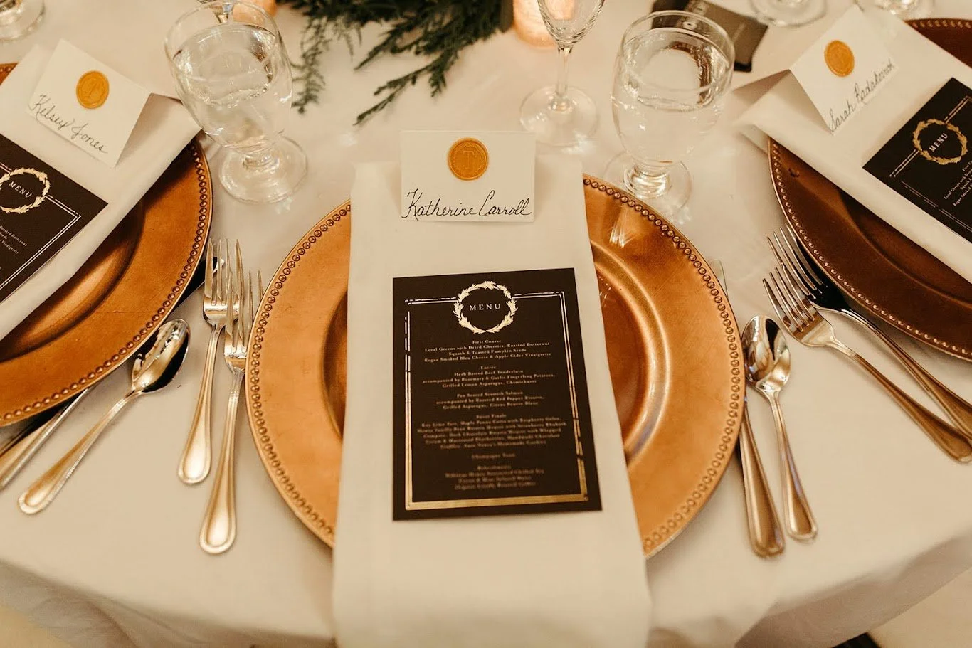 Wedding place setting with a gold charger plate, printed menu card, and napkin at a reception table.