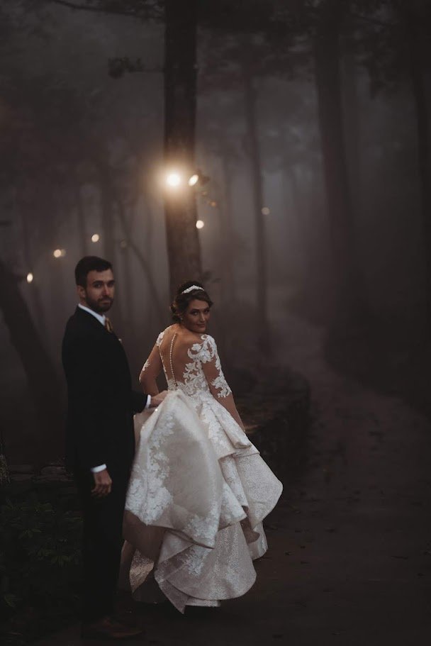 Bride and groom standing together in a foggy forest for a moody wedding portrait.