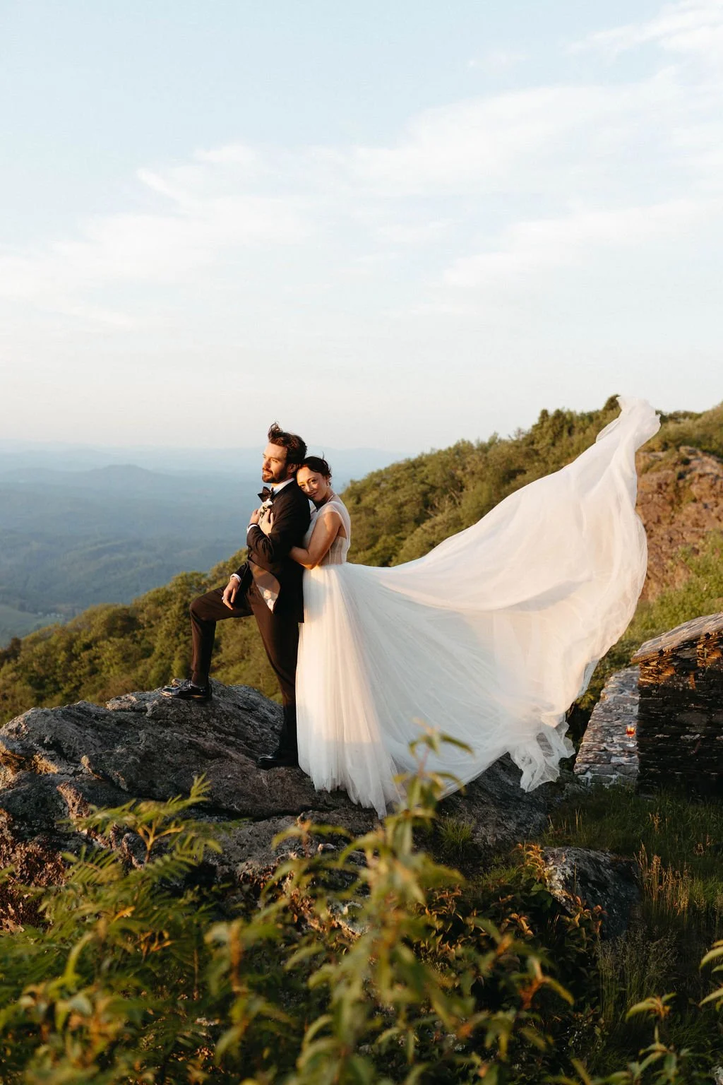 Bride and groom exchanging rings during a mountain overlook wedding ceremony with an officiant and bridesmaid nearby.