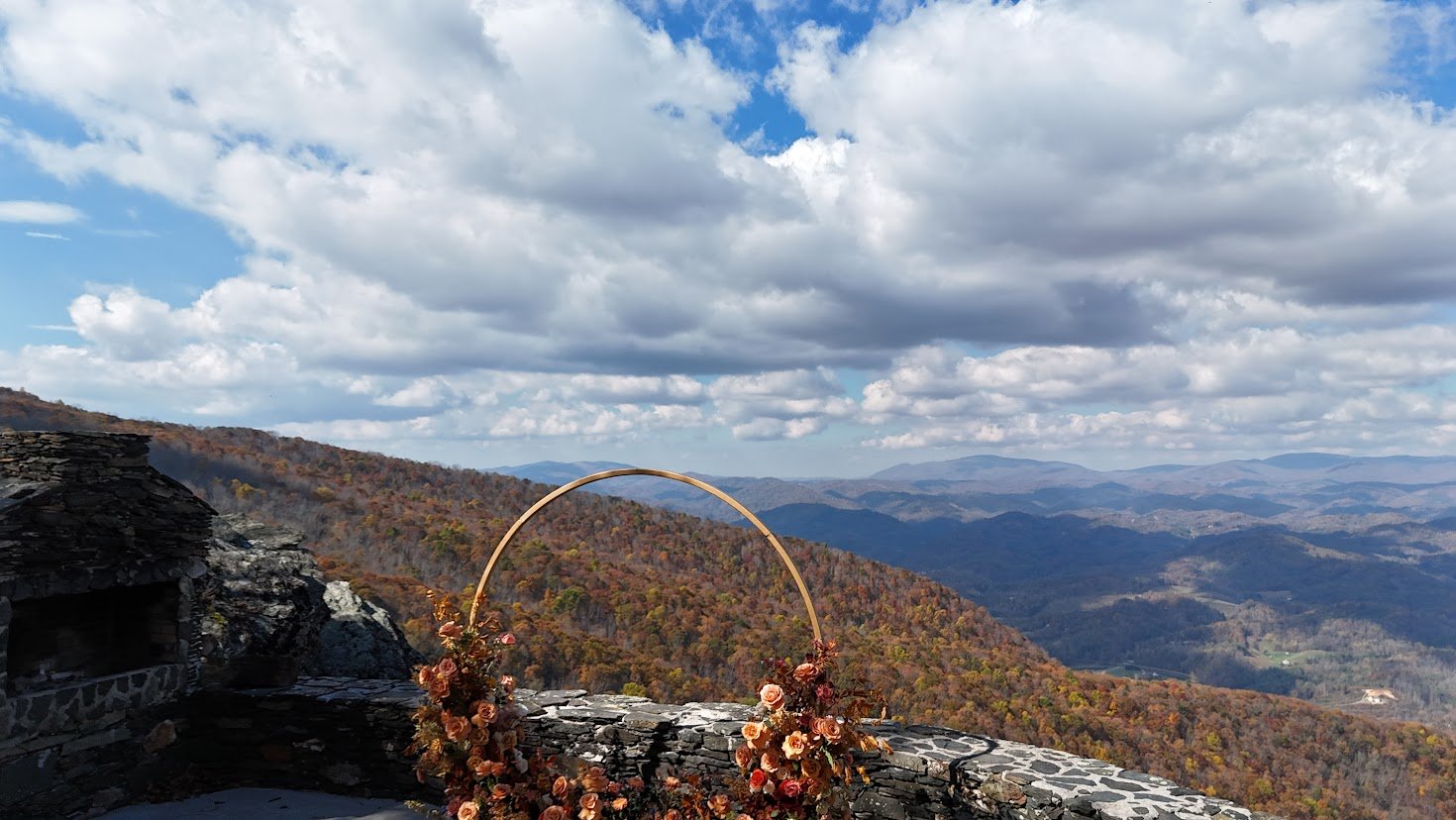 Scenic mountain overlook with a circular wedding arch and dramatic clouds in the sky