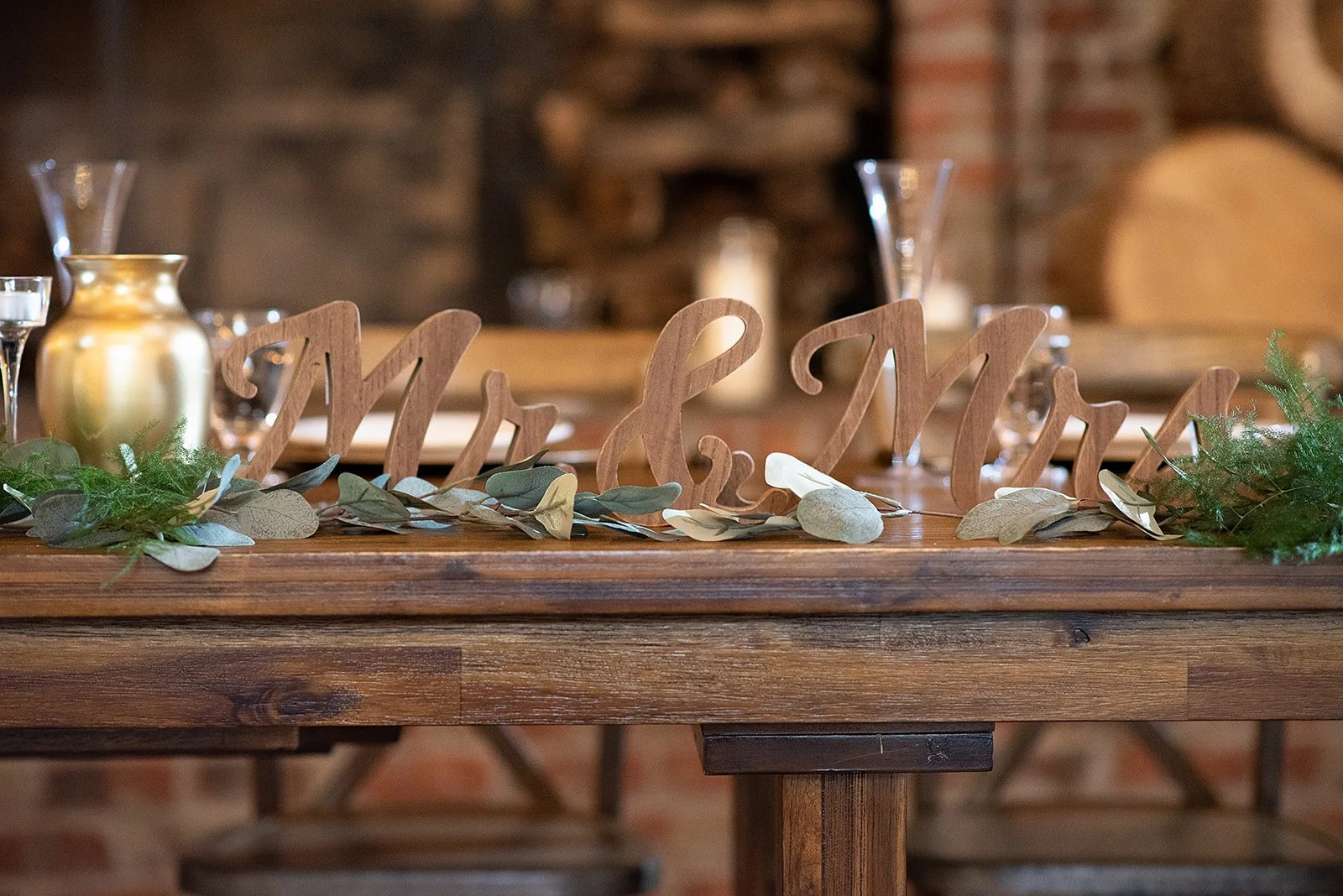Wooden “Mr & Mrs” sign displayed on a sweetheart table with greenery garland.