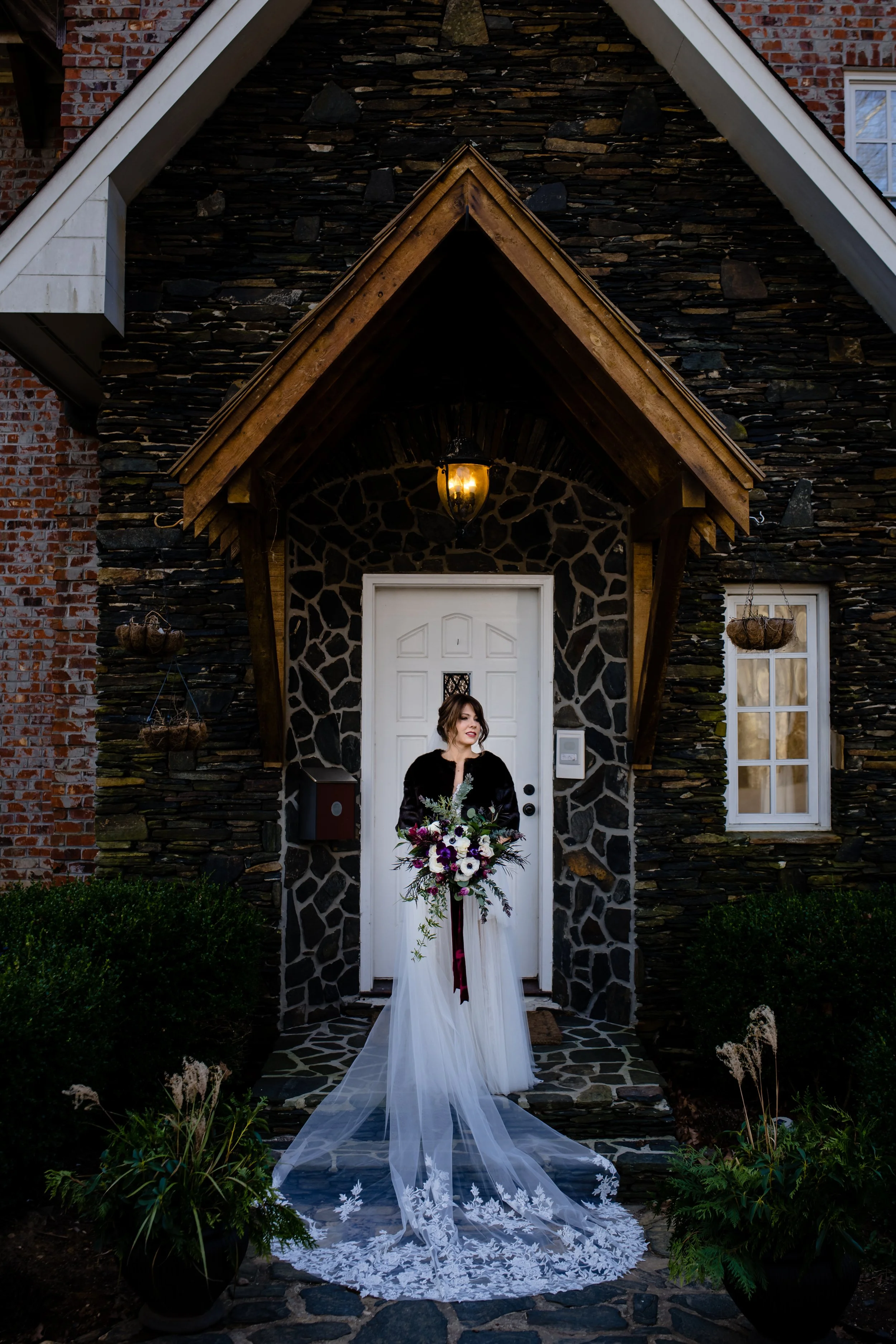 Bride holding a bold floral bouquet outdoors with mountains and trees in the background.