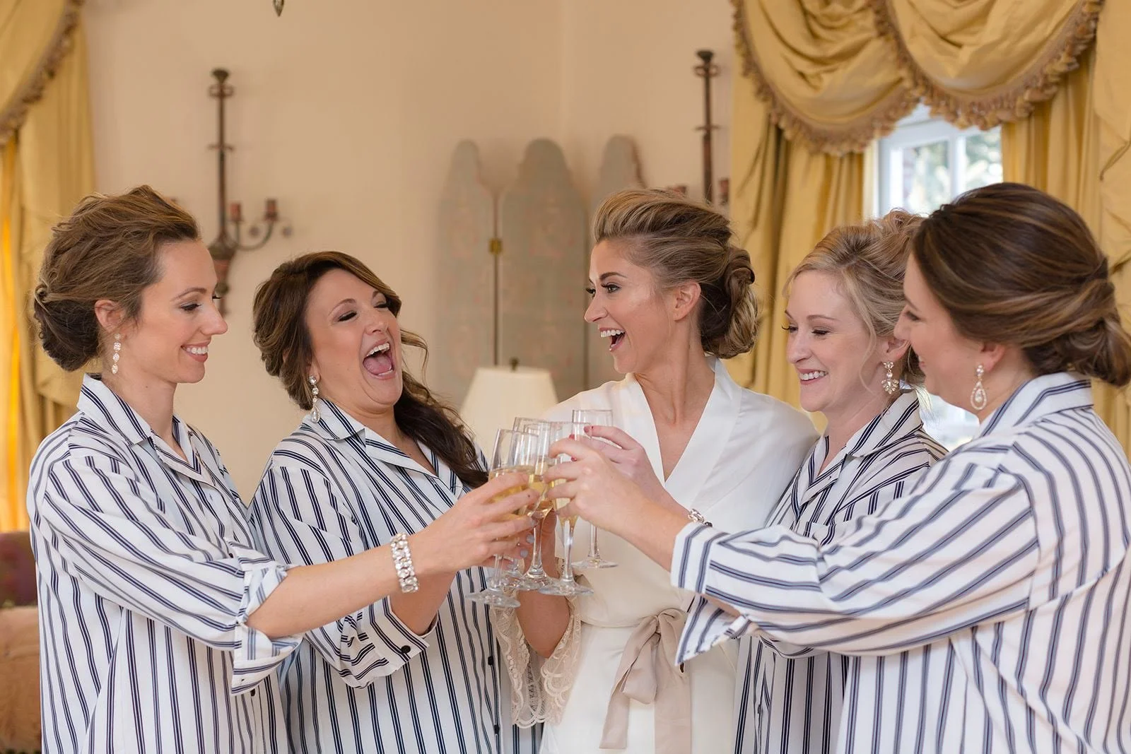 Bridesmaids and bride toasting in matching pajamas during getting ready.