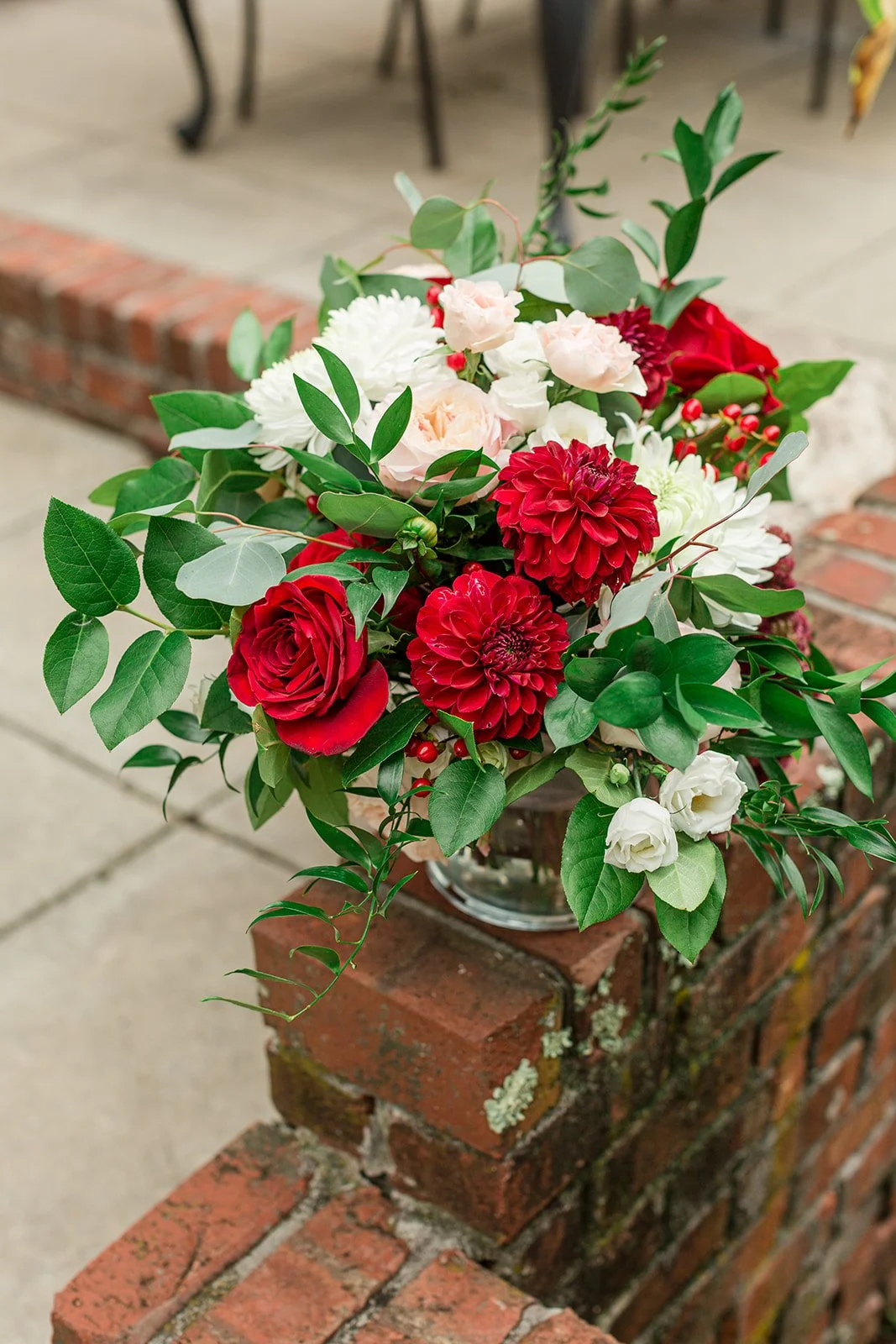 Wedding bouquet with red roses, red dahlias, white flowers, blush roses, berries, and greenery.
