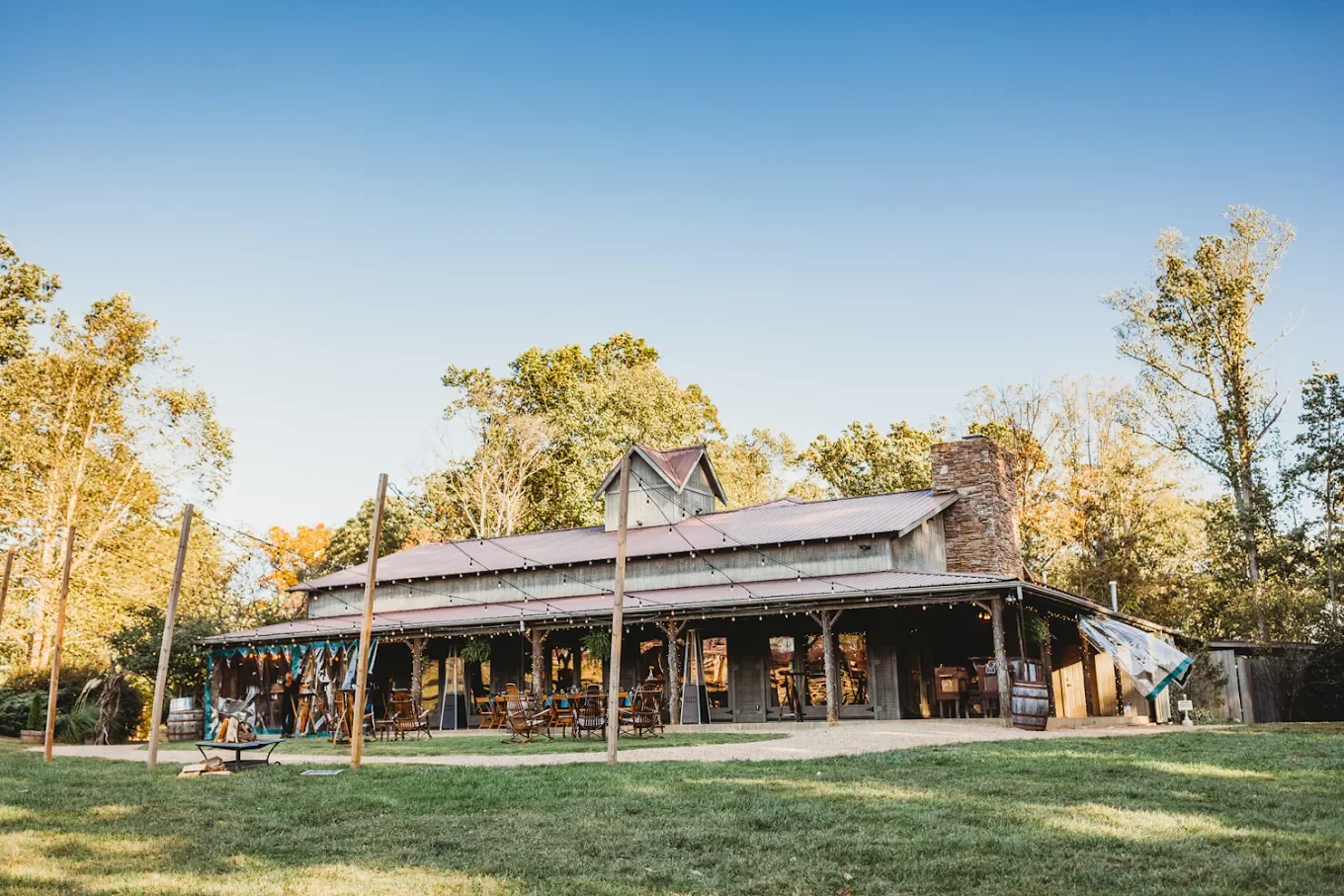Rustic farm wedding venue exterior with an open-air barn, string lights, and a grassy lawn