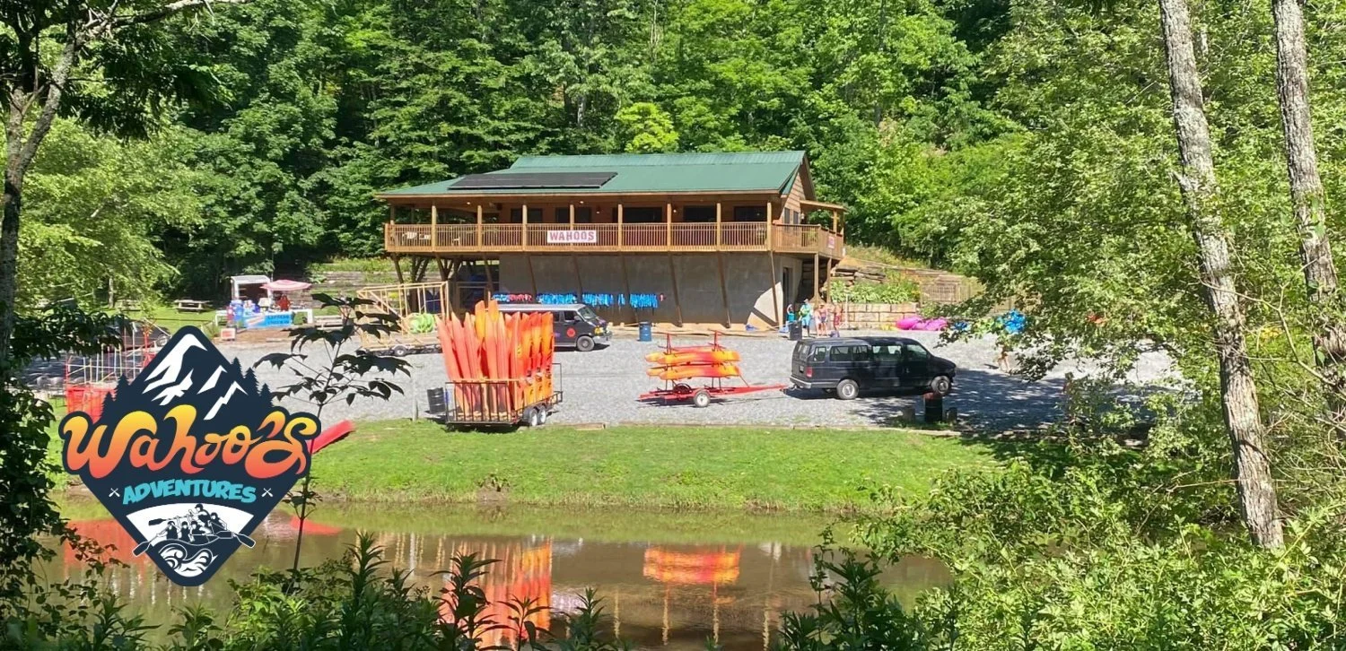 Wahoos Adventures river outpost building with stacked orange rafts and gear outside