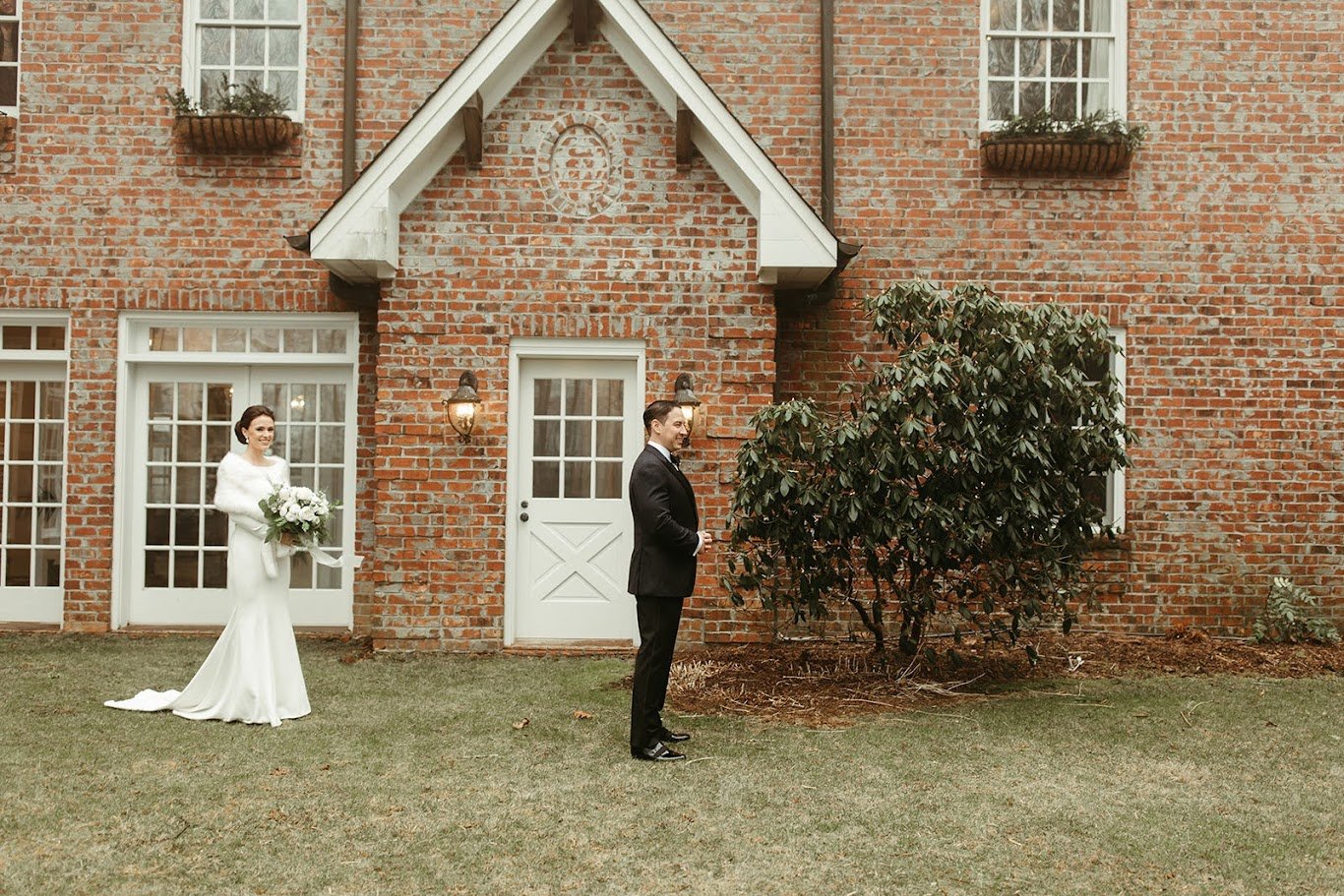 Bride approaching the groom for a first look outside a brick venue courtyard.