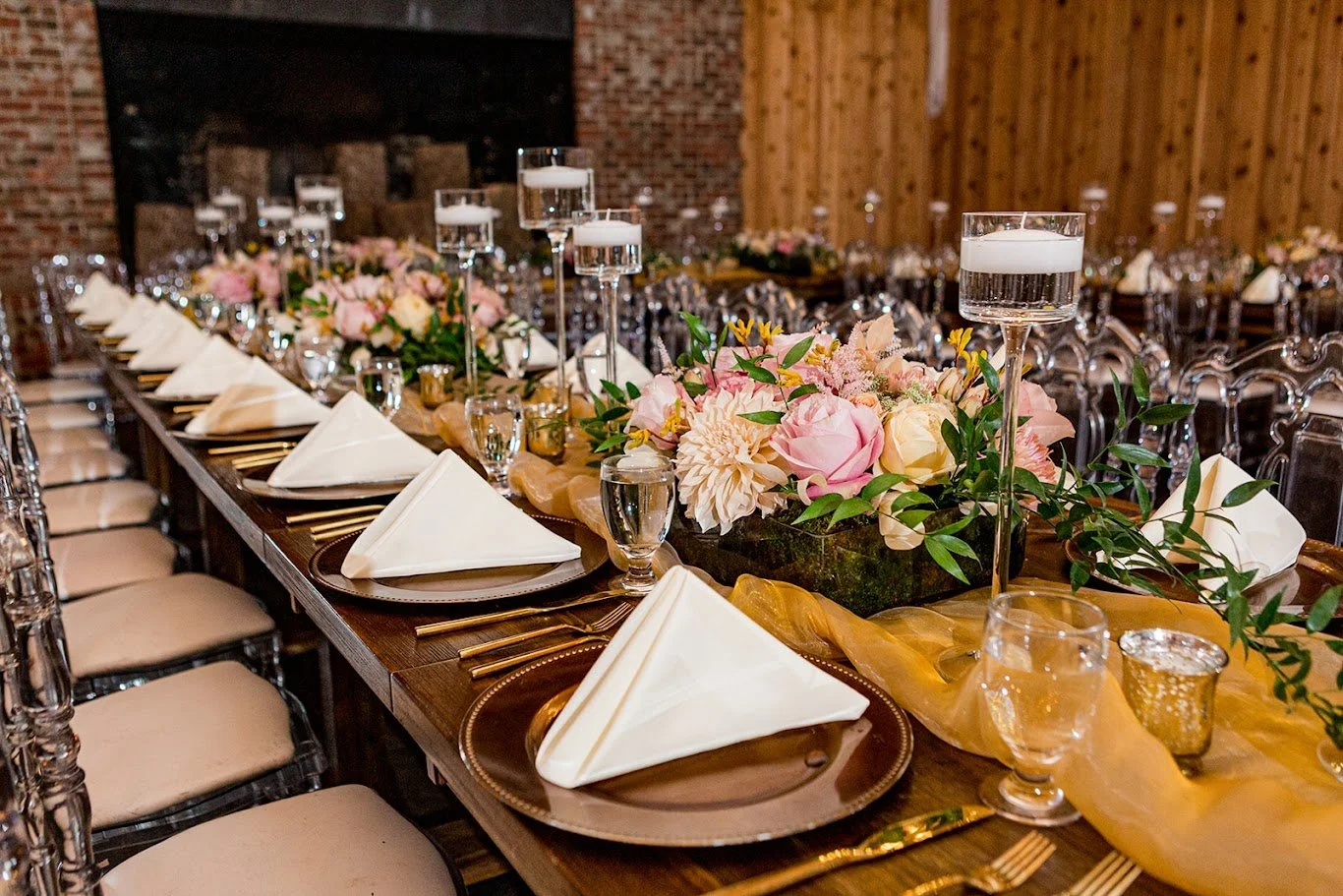 Close-up of reception table settings with folded white napkins, blush florals, and greenery