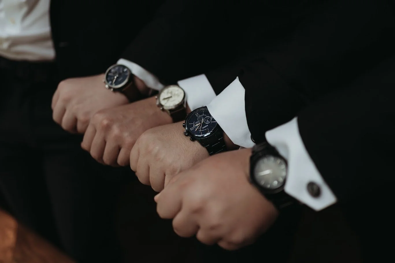 Groom in a dark suit sitting in a chair by a window holding a drink, showing bright orange socks