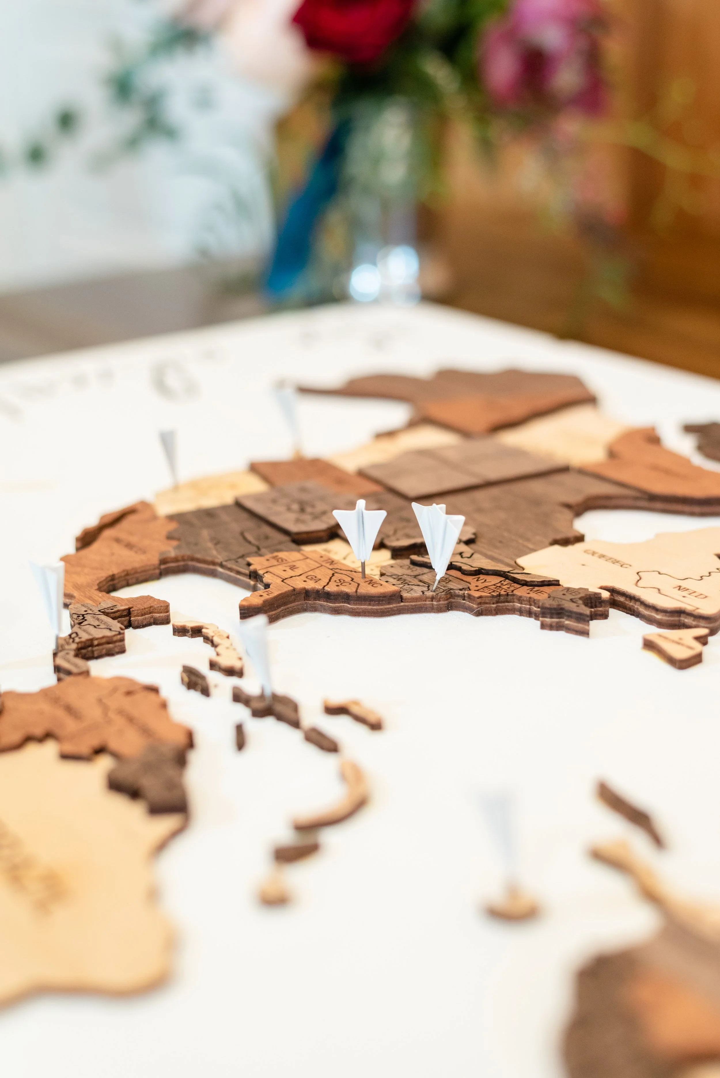 Wooden world map guestbook with pins and paper airplanes for a travel-themed wedding.