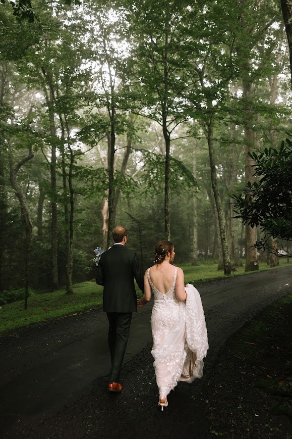 Bride and groom walking together down a forest road after the ceremony.