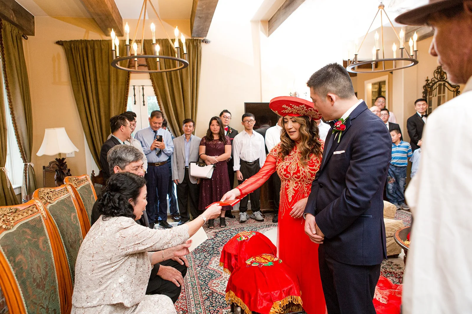 Group holding a red umbrella indoors during an Indian wedding celebration