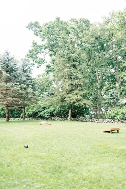 Open grassy lawn with cornhole boards set up for outdoor wedding lawn games
